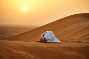 arabo che prega nel deserto